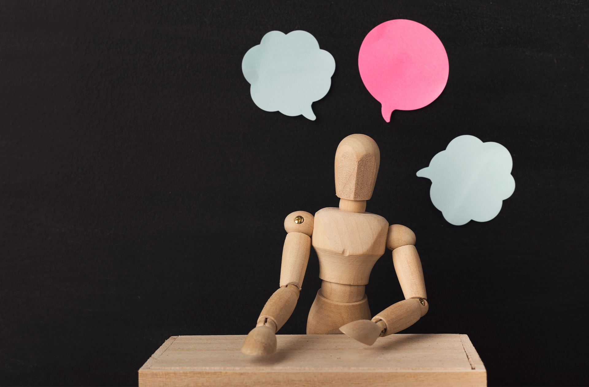 Wooden man figure mannequin with blank speech bubbles on black background, objects, nobody. Thoughts, thinking, ideas concept